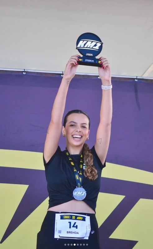 Atleta erguendo troféu no pódio